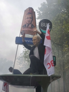 Un manifestant portant un masque de Bernard Arnaud, pêrché sur un abirbus